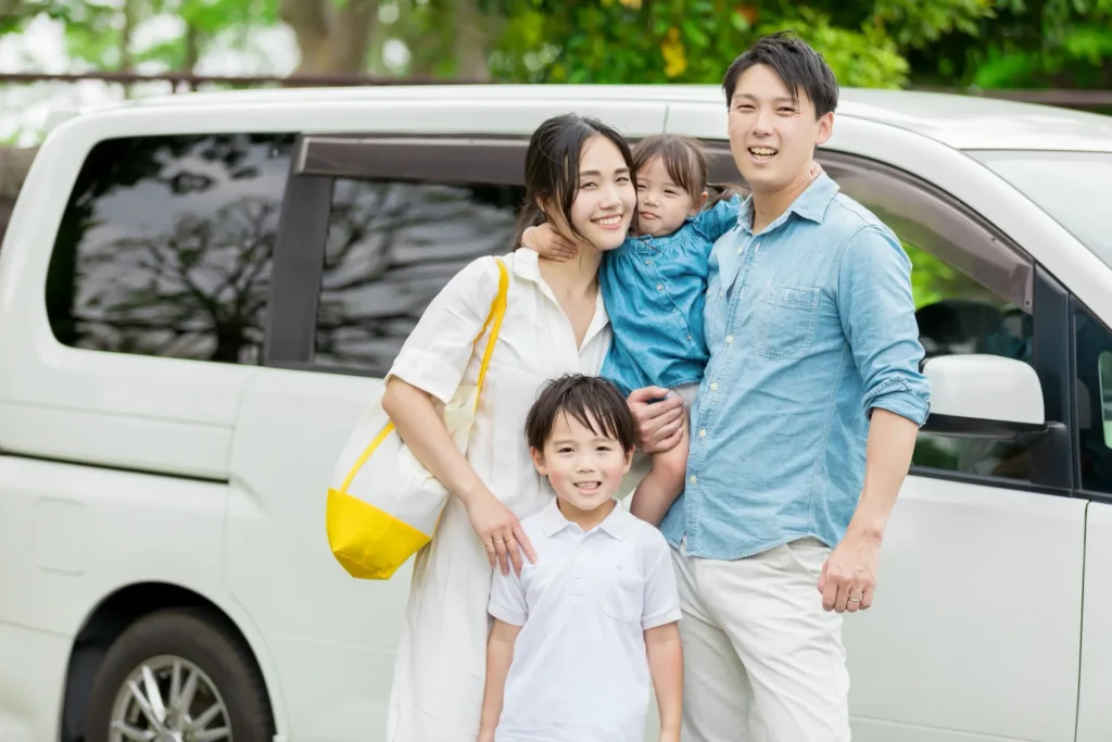 車の前で笑顔の家族